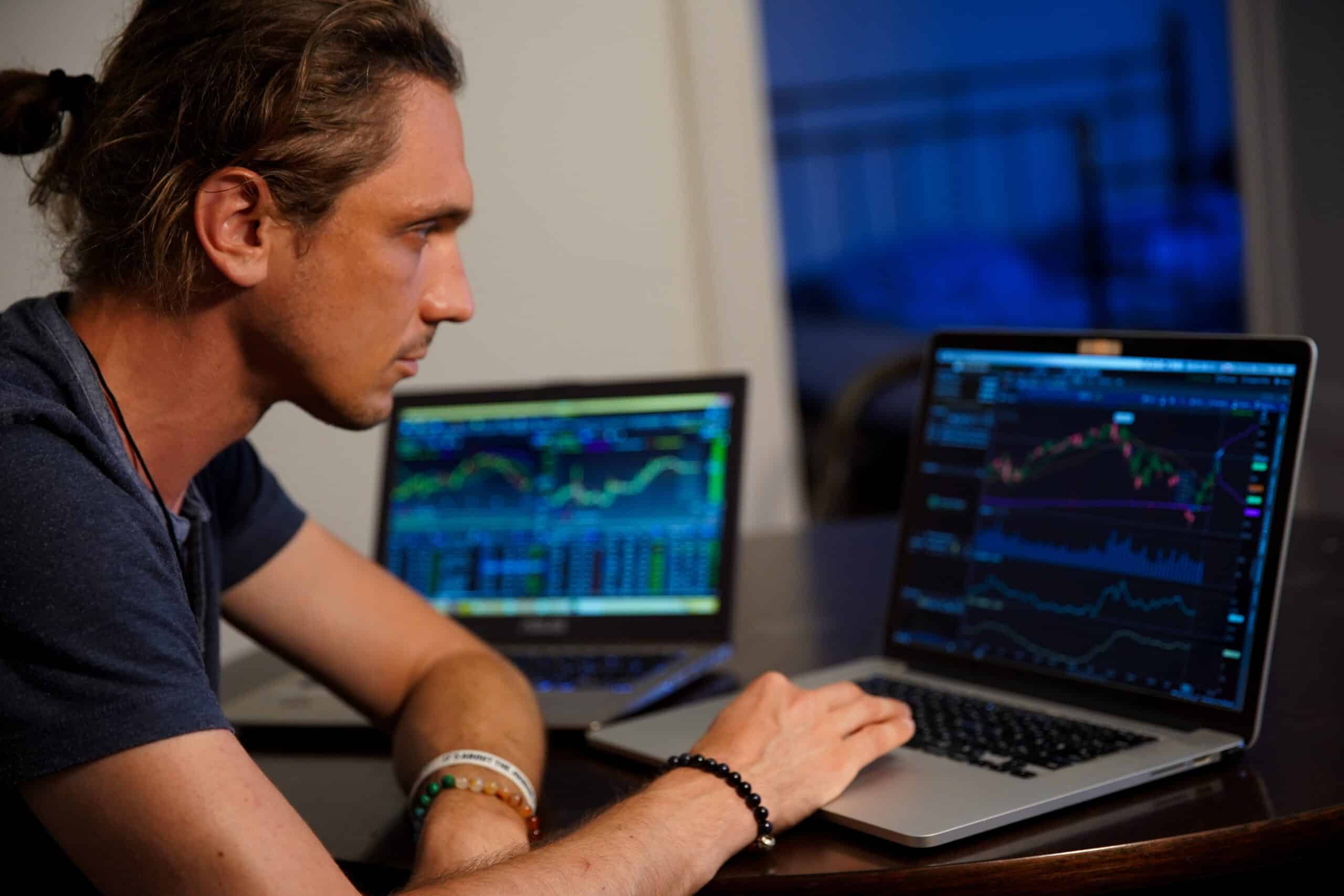 arnaque aux formations de trading : jeune consultant une formation de trading sur un ordinateur avec une expression inquiète